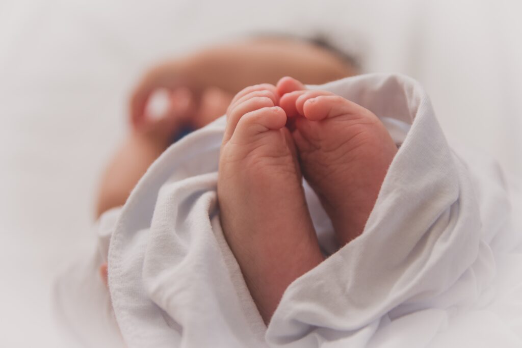 A close up of a newborn infants feet with their arms in the background. Fertility Support trying to conceive