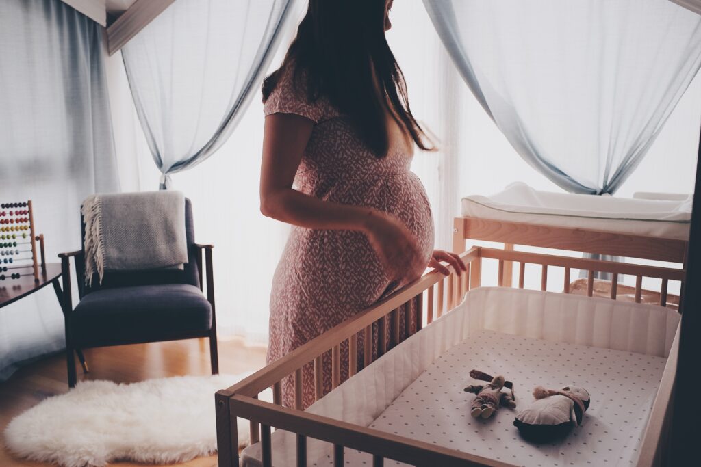 An expectant mother looks over her empty crib waiting the arrival of her unborn baby. wisconsin infertility treatment, Fertility Support 