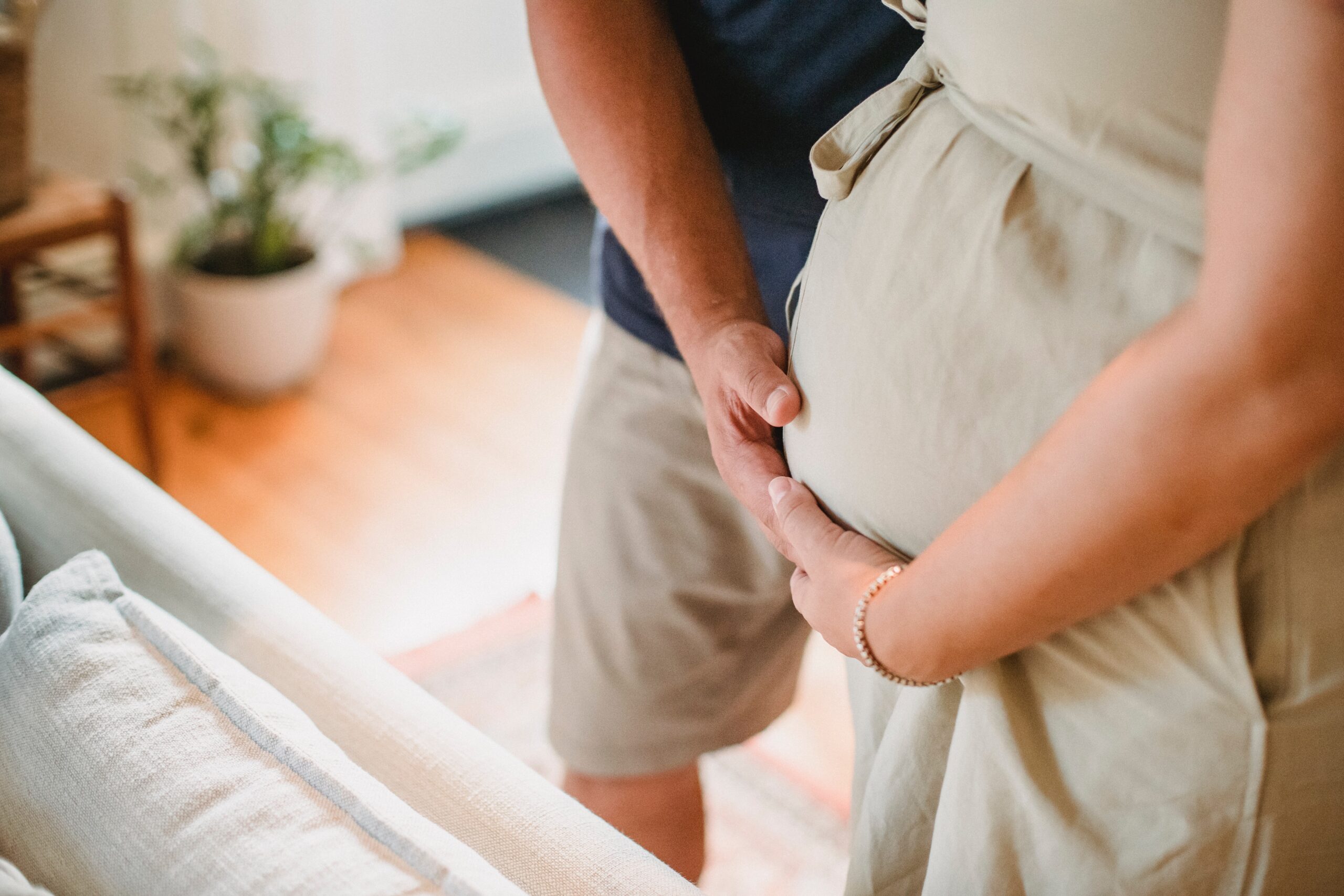 A woman expecting her child holds her stomach while her partner places one hand on her stomach, wisconsin fertility coach, wisconsin infertility treatment, understanding your menstrual cycle
