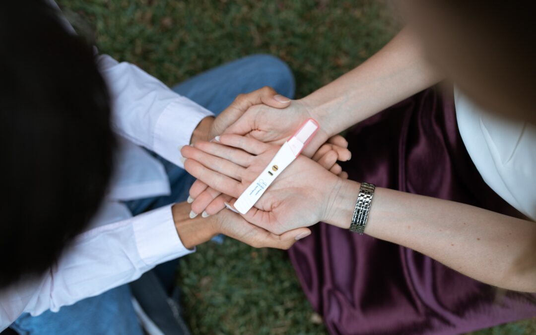 partners hold their positive pregnancy test in their hands between them, fertility coaching, getting pregnant, staying pregnant