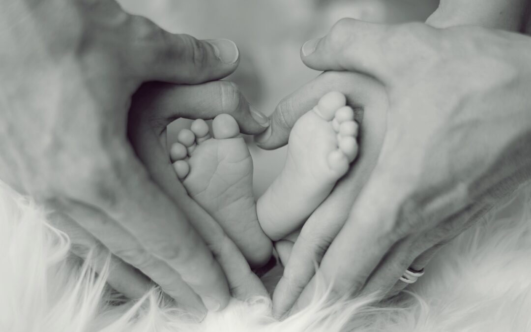 mom and dad holding an infants feet in a heart shape. Influence of Chiropractic Care on Fertility