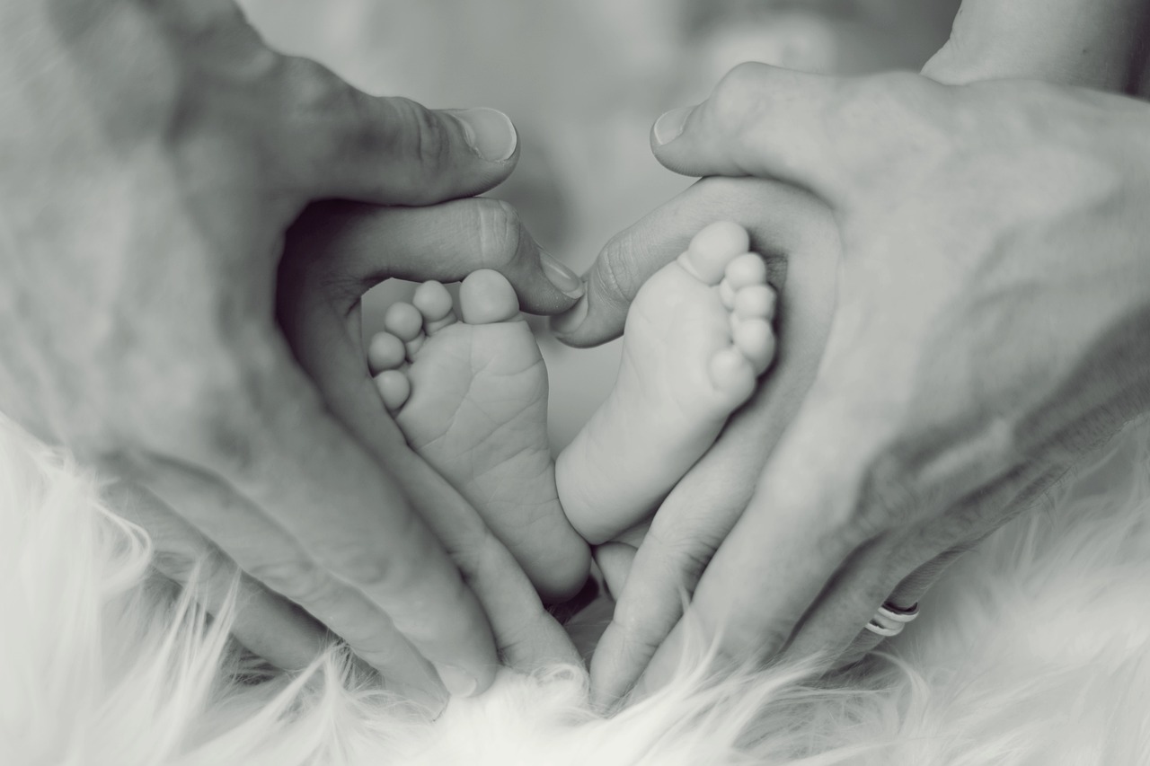 mom and dad holding an infants feet in a heart shape. Influence of Chiropractic Care on Fertility