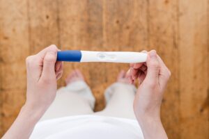a person holds a positive pregnancy test. lifestyle and fertility, fertility coaching, infertility 