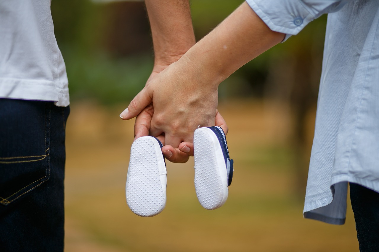 husband and wife holding an infants shoes between them. fertility and chiropractic care. 