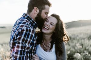 Man and woman kissing in a field after they find out they are pregnant after fertility issues